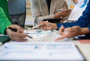 A professional working at a modern office desk, sketching out a project flowchart and organizational diagram on paper with a pen.