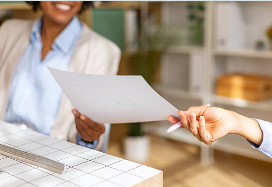 A close-up shot focusing on a document being handed from one professional to another over an office desk.